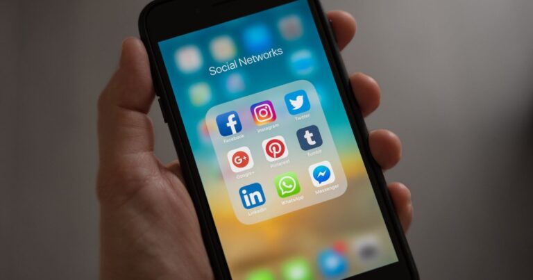 Hand holding a smartphone showing Instagram, Facebook and other social media apps